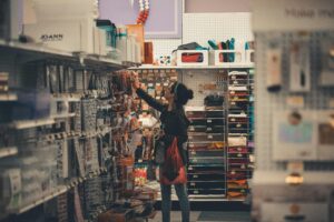 mother shopping for school supplies and taking an item off the hanger.