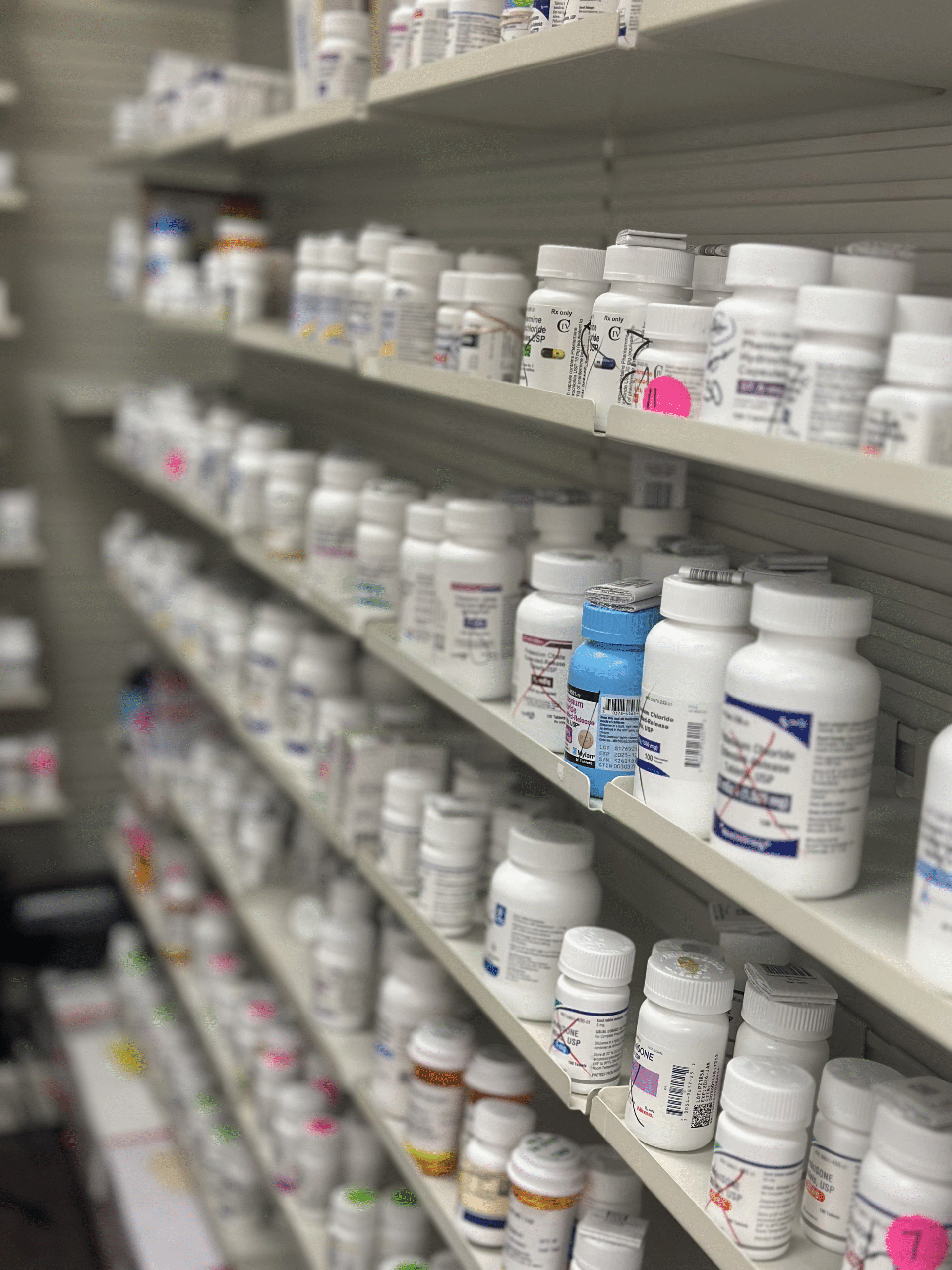 A shelf with white prescription bottles in the pharmacy