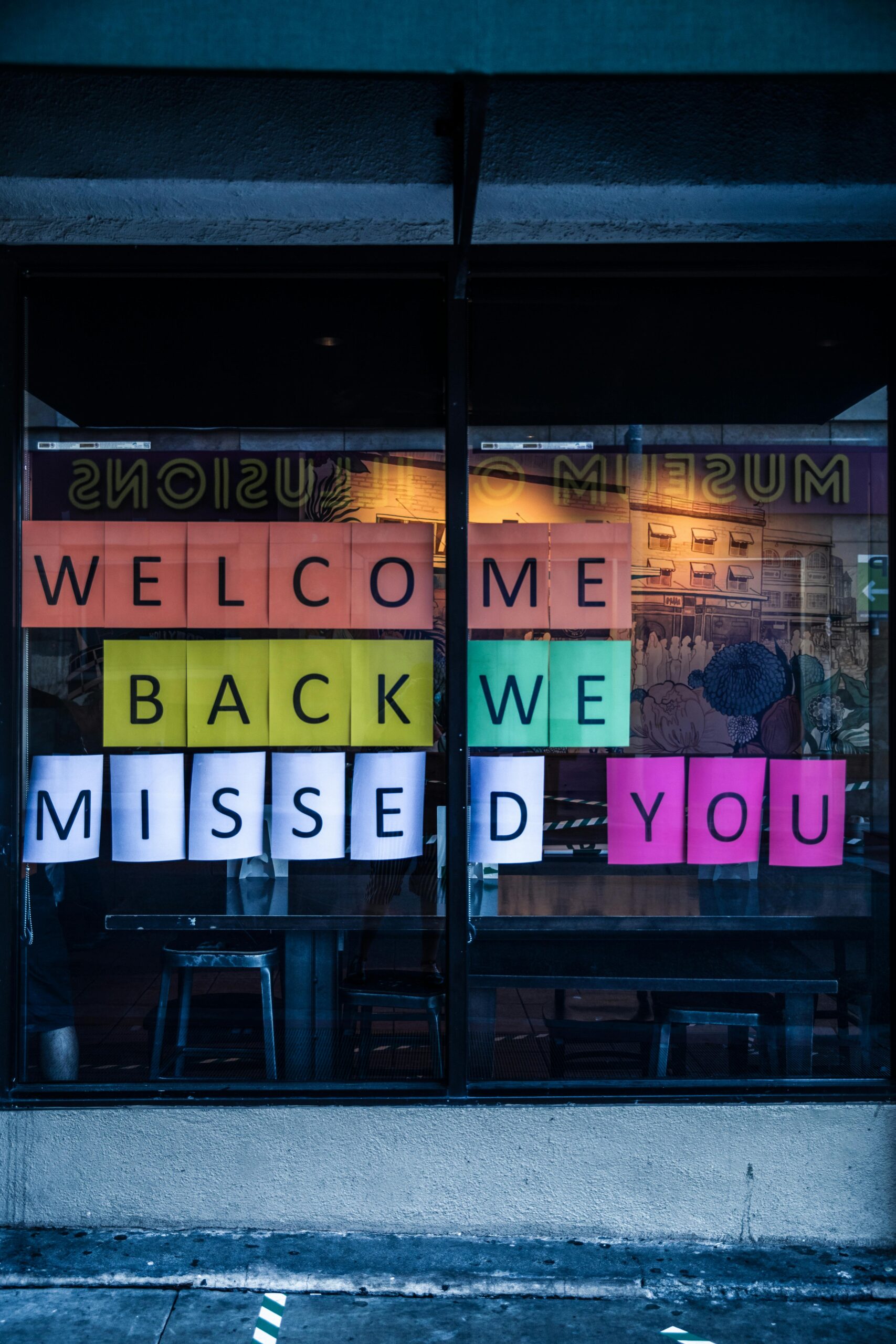school window with a sign made of sheets of papers that spell out "welcome back we missed you".