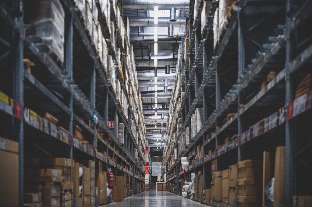 Large warehouse aisle with tall industrial storage racks filled with boxes and palletized inventory